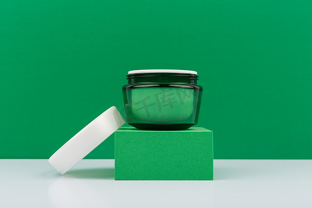 绿色打开的奶油罐，绿色讲台上有白色帽子，绿色背景