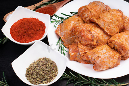 生鸡肉被红色、番茄腌料和香料包裹在白盘子里。