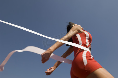 年轻女运动员在晴朗的蓝天下穿越终点线的低视角