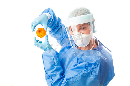 病理学摄影照片_穿着生物安全服和 PPE 的病理学科学家举着培养皿