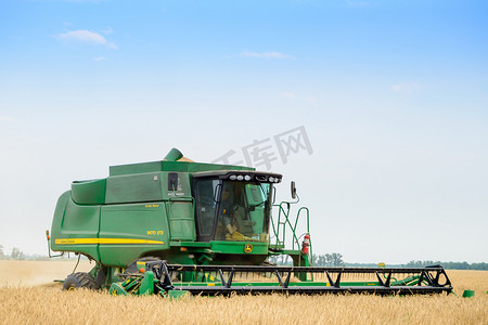 约翰迪尔联合收割机在田间收割小麦。