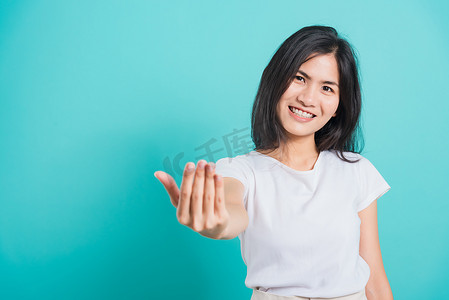 邀请手势摄影照片_微笑的女人穿着白色 T 恤，用手做手势邀请