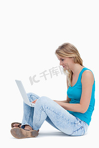 坐在地上用笔记本电脑打字的女人的侧视图