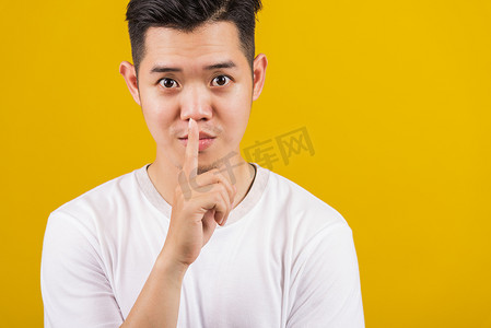 手放在嘴唇上摄影照片_将食指放在嘴唇上的男人要求保持沉默或秘密打手势