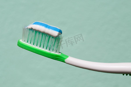 黑茶牙膏摄影照片_在绿色 b 上关闭牙刷和一些牙膏的视图