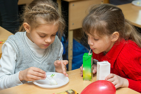 两个孩子在学校的聚会上喝果汁吃蛋糕