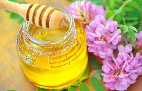 装满蜂蜜的玻璃罐和粘着粉红色和白色相思花的蜂蜜