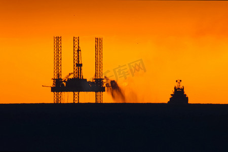 在日落时的石油平台与燃烧的火炬。石油平台的牵引。