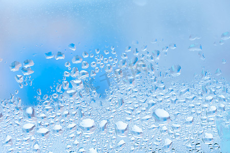 带有大滴水或蓝色雨的湿玻璃。
