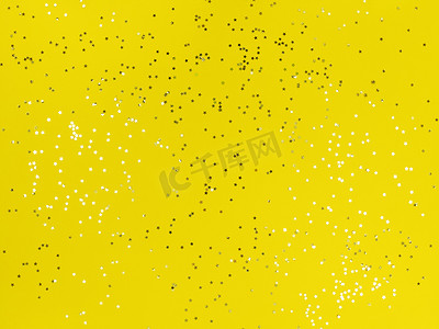 星星背景黄色摄影照片_五彩纸屑星星在黄色背景上闪闪发光。