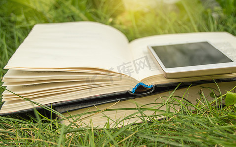 夏天教育摄影照片_打开草地上的书，在阳光、户外、夏天的背景下打电话