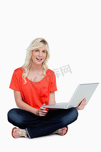 盘腿坐着的年轻女人拿着她的笔记本电脑