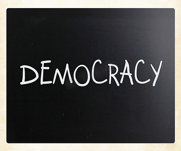用白色粉笔在黑板上手写的“民主”一词