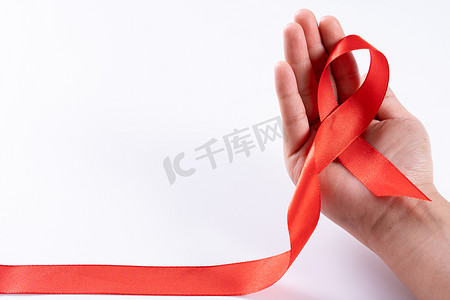 帮助提高认识，女人手拿着白色背景上的红丝带，上面有文字的复制空间。