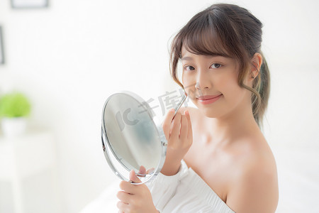 美丽的肖像年轻亚洲女人看着镜子应用 mak