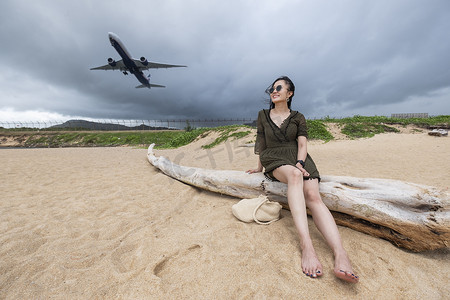 海滩上的女游客在岛上观看着陆飞机