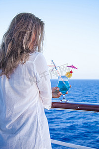 蓝色冷饮摄影照片_拿着冷饮，欣赏海景的漂亮女孩