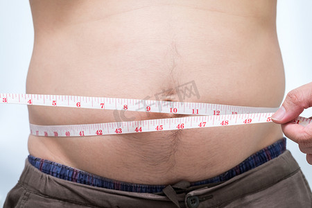 肥胖的亚洲男人用腰围测量他的肚子
