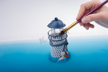小帆船图标摄影照片_水中的画笔和小模型灯塔