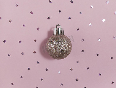 粉色纸上闪闪发光的圣诞树球和五彩纸屑星星。