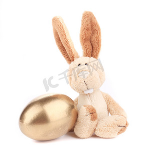 金色兔子摄影照片_带金蛋的白色玩具兔。