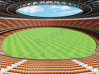 垂直俯拍足球场摄影照片_美丽的现代圆形澳式足球场，设有橙色座椅和贵宾包厢