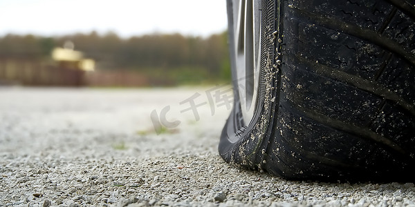 道路服务摄影照片_汽车后轮胎扁平的特写镜头。