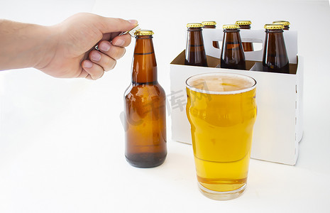 pilsner摄影照片_一个人打开 Pilsner Style Lager 棕色瓶装啤酒和一品脱啤酒