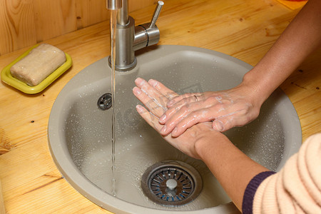 肥皂水洗手摄影照片_女孩的手在厨房水槽里用肥皂彻底洗手