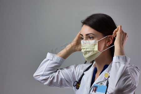 女性医疗保健专业人员展示正确戴上口罩以防止冠状病毒感染。