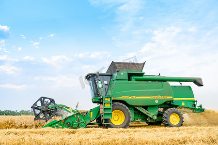 田间收割摄影照片_约翰迪尔联合收割机在田间收割小麦。