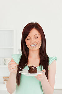 有魅力的红发女人在厨房里吃蛋糕