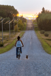 农场女孩带着狗骑自行车在路上