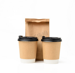 带盖摄影照片_两个带塑料盖的棕色纸杯和一个食品纸袋，生态可回收食品包装