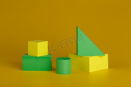 黄色几何创意摄影照片_深黄色背景下黄色和绿色图形的双色调几何静物