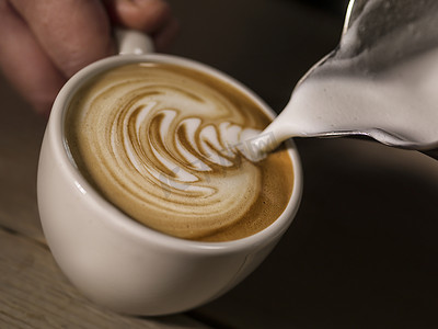 咖啡师的手制作拿铁或卡布奇诺咖啡倒牛奶制作拿铁艺术
