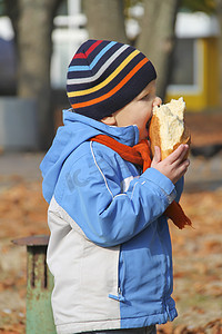 孩子在公园秋天散步时吃面包