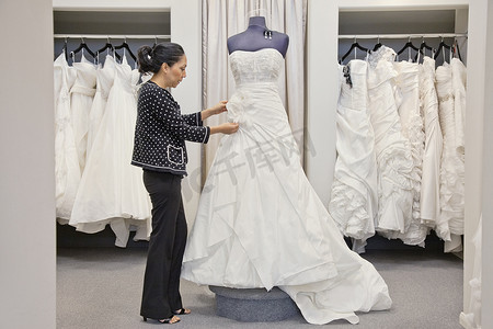 婚纱店一名成熟员工调整优雅婚纱的侧视图