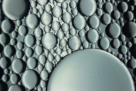 水面气泡摄影照片_漂浮在水面上的油圈抽象宏观背景。