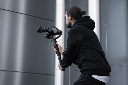 年轻的专业摄像师在 3 轴万向稳定器上手持专业相机。