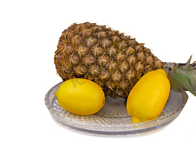 福利产品摄影照片_菠萝和柠檬放在白色背景的盛肉盘上。