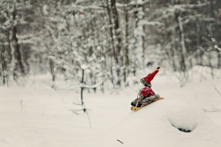玩具圣诞老人在白雪皑皑的森林里的雪橇上