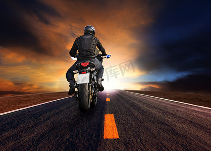 男子骑摩托车在高速公路上迎着美丽的夕阳西下