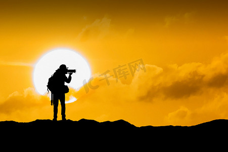 摄影师摄影照片_摄影师在日落时用相机的剪影。