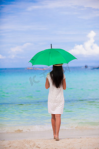白色沙滩上带伞的年轻女孩