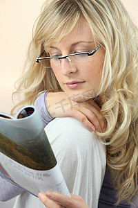 戴眼镜的迷人女人正在看杂志