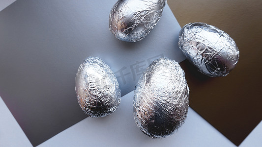 银色铝箔球摄影照片_在银色背景上的铝箔鸡蛋。