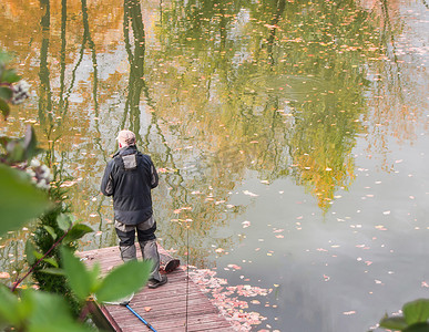 一名男性社会工作者生态学家站在河岸上观察城市池塘的水况。