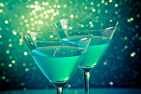 深绿色浅色散景上的蓝色鸡尾酒杯