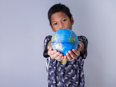 拿着地球仪的男孩站在前面展示新一代继续发展我们世界的力量。